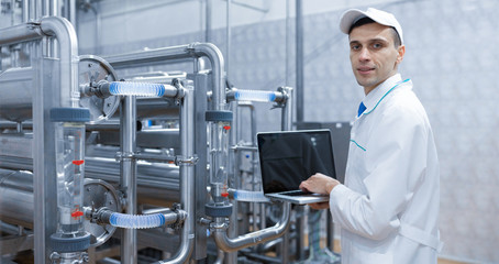 Wall Mural - Technologist with a laptop in his hands at the dairy plant