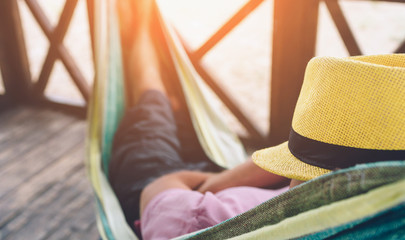 young man lying in hammock at sunny beach by ocean and sleeping. he hold had on face. young man chil