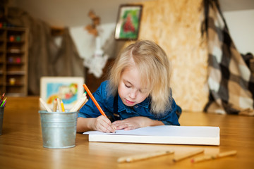 little girl lying on the floor and drawing with colored pencils