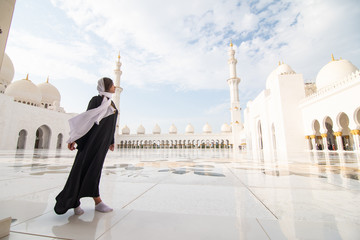 Traditionally dressed arabic woman wearing black burka visiting Sheikh Zayed Grand Mosque in Abu Dhabi, United Arab Emirates.