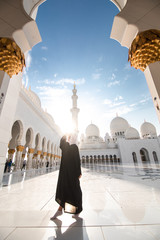 Wall Mural - Traditionally dressed arabic woman wearing black burka visiting Sheikh Zayed Grand Mosque in Abu Dhabi, United Arab Emirates.