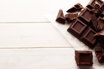 A large bar of black chocolate on a white wooden background with space for text.