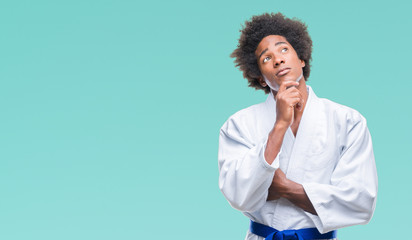 Canvas Print - Afro american man wearing karate kimono over isolated background with hand on chin thinking about question, pensive expression. Smiling with thoughtful face. Doubt concept.