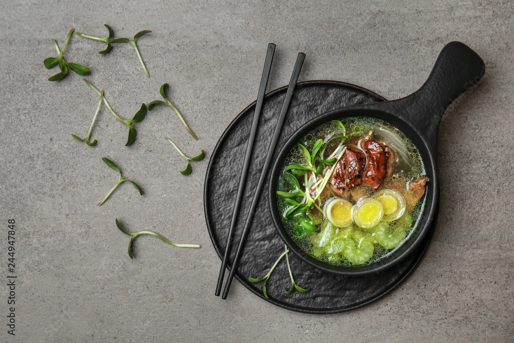 Tasty Chinese soup in bowl on grey table
