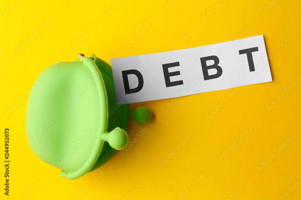 Paper with word DEBT and wallet on color background