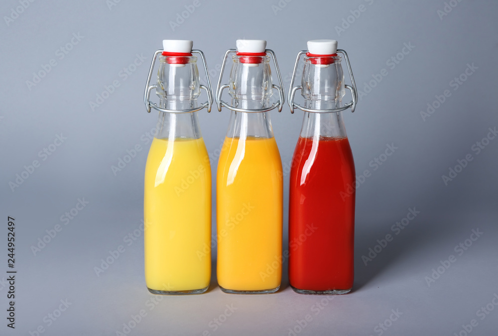 Bottles of healthy juices on grey background