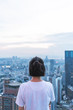 Young woman looks out over the city at the top of the building