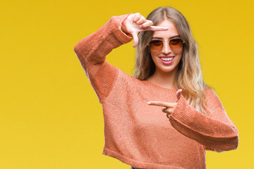 Poster - Beautiful young blonde woman wearing sunglasses over isolated background smiling making frame with hands and fingers with happy face. Creativity and photography concept.