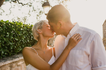 young beautiful couple girl in white dress man in white shirt walks at sunrise on the seashore