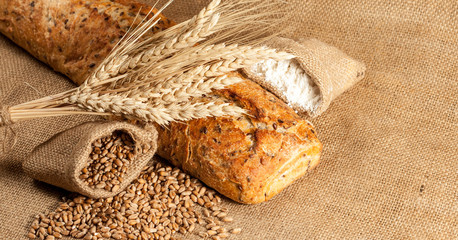 Retro bread in rustic style background.Fresh traditional bread on wooden ground with flour in a sack.