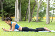 © montira - Young attractive beautiful woman in blue and black sportswear practicing and exercise in yoga style at the park.