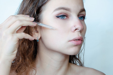  Beautiful young woman with piercing  holding a serum pipette.