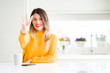 © Krakenimages.com - Young beautiful woman drinking a cup of coffee at home showing and pointing up with fingers number three while smiling confident and happy.