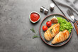 Fried chicken breasts served with sauce and garnish on grey table, top view. Space for text