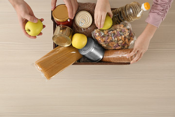 Volunteers taking food out of donation box on table, top view