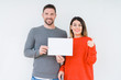 © Krakenimages.com - Young couple holding blank sheet paper over isolated background pointing and showing with thumb up to the side with happy face smiling