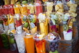Fototapeta Boho - Close-up Mix Fruits juice in a plastic Glass on Wooden shelves at Street food market,Thailand.