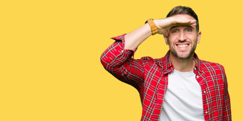 Handsome man wearing casual shirt very happy and smiling looking far away with hand over head. Searching concept.