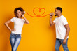 © Prostock-studio - Young black couple with can phone on orange background
