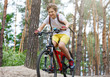 © Natali - Child teenager in white t shirt and yellow shorts on bicycle ride in forest at spring or summer. Happy smiling Boy cycling outdoors Active lifestyle, hobby