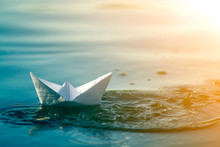 Close-up Of Simple Small White Origami Paper Boat Floating In Blue Clear River Or Sea Water Under Bright Summer Sky. Beauty Of Nature, Freedom, Dreams And Fantasies Concept.