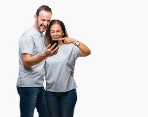 Canvas Print - Middle age hispanic couple texting message on smartphone ver isolated background very happy pointing with hand and finger