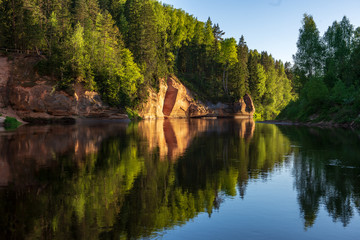 blue sky and clouds reflecting in calm water of river Gauja in latvia in autumn