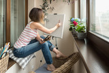 Fototapeta Lawenda - A female artist painting on canvas on her studio balcony.