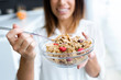 © nenetus - Pretty young woman showing cereals to camera while eating in the kitchen at home.