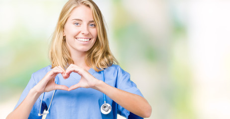 Beautiful young doctor woman wearing medical uniform over isolated background smiling in love showing heart symbol and shape with hands. Romantic concept.