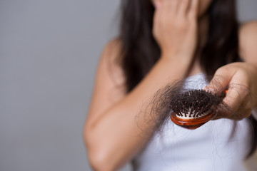 Wall Mural - Healthy concept. Woman show her brush with long loss hair and looking at her hair.