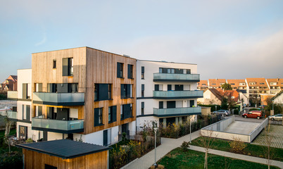 Modern townhouses in a residential area with multiple new apartments buildings surrounded by green outdoor facilities with cars parked on the street