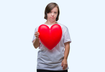 Sticker - Young adult woman with down syndrome holding red heart over isolated background with a confident expression on smart face thinking serious