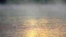 Golden Light Shimmering On Water With Fog Rising From Pond Or Lake