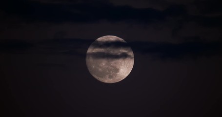Wall Mural - Beautiful shot of a full moon peaking through some clouds at dusk in 4K.