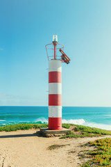 Wall Mural - red white lighthouse on atlantic ocean shore