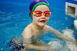 Boy in a blue cap and glasses is sitting on the stairs in the pool.