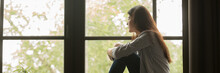 Horizontal Photo One Teen Lonely Woman Sitting At Home On Sill Look At Window Feels Sad Depressed Frustrated Thinking About Problem Panoramic Banner For Website Header Design With Copy Space For Text.