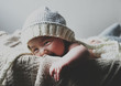 © Yumiko Kinoshita - Portrait of smiling baby boy wearing knit hat lying in basket