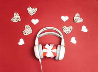 Wall Mural - White headphones with gift box and decorative hearts on a red background. St. Valentines Day music gift concept.