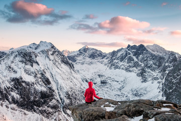 Red mountaineer relaxing on rock with magnificent mountain at evening