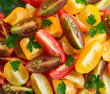 Fresh vegetable salad of mixed tomatoes of different colors. Red, yellow and brown tomatoes cut on plate