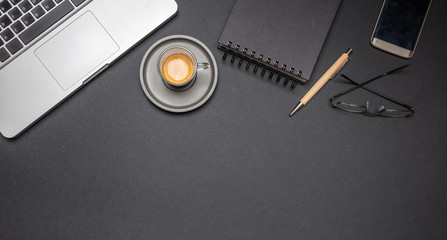 Computer laptop and mobile phone on black office desk, top view, copy space