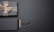 © Rawf8 - Black gift box with shiny ribbon on black office desk, top view