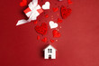 © WindyNight - Miniature white toy house with hearts and gifts on red background.