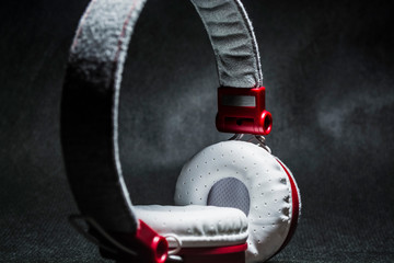 Poster - White earphones for listening of music. Red plastic and skin. On a black background. Modern technologies. Fashionable appearance.