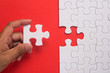 © mimiarifa - Close up of hand placing the last jigsaw puzzle piece on red background. Business and team work concept.