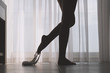 Bottom view of silhouette of beautiful woman with sexy legs taking off her white panties in a room against the backdrop of curtains