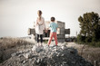 © ruslanshug - two poor refugees children standing with hope together holding hands on ruins of destroyed during war fighting home house