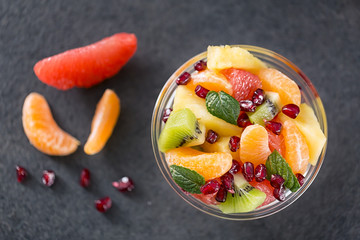 Bowl of healthy fresh fruit salad on black background.